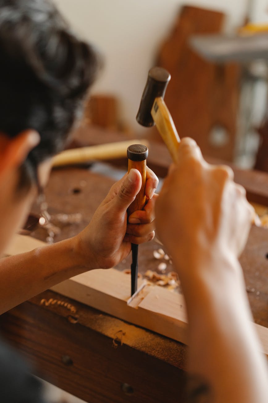 craftsman hammering chisel into wooden plank
